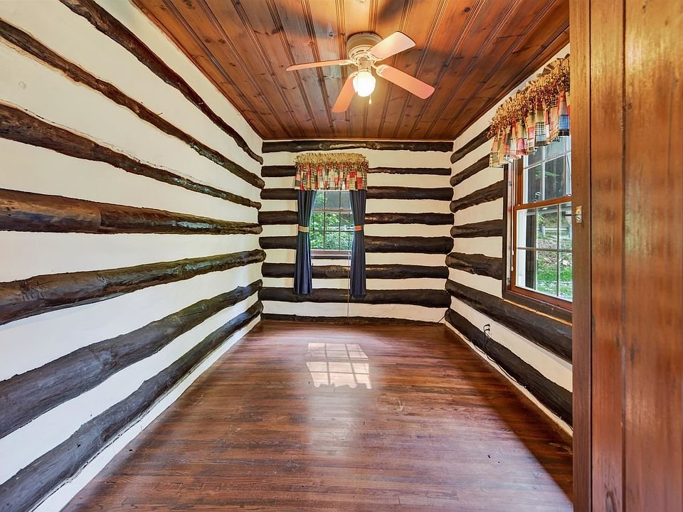 Room with exposed log walls and wood flooring