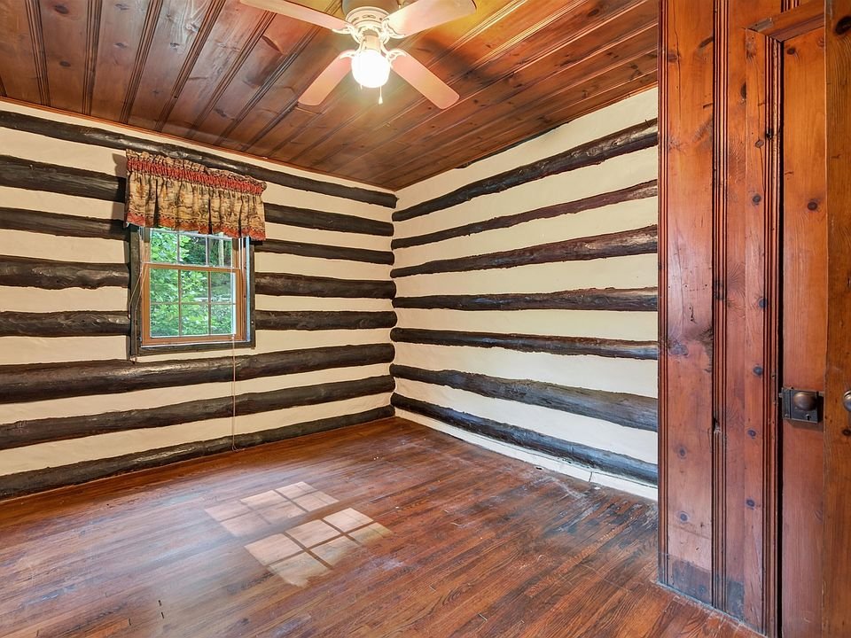 Second room with exposed log walls and wood flooring